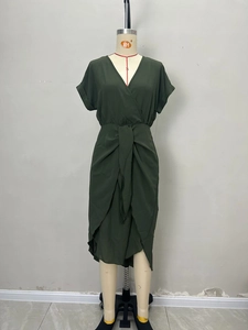 Detail view of deep green wrap dress showing deep V-neck, waist tie and tulip hem design