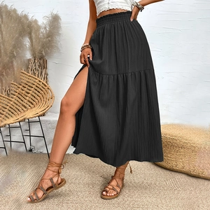 Detail of high waist elastic smocked skirt with ruffles and side slit in black