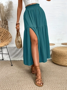 Detail of high-waist maxi skirt with ruffle layers, side slit, and textured fabric