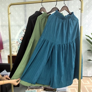Detail of high-waist pleated skirts in black, green and blue with smocked elastic waist