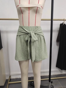 Women's sage green high-waisted wide-leg shorts with tie-waist bow and crinkle fabric