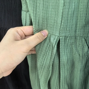 Detailed close-up showing the pleated texture and side hidden pocket of the green skirt