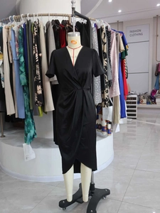 Close-up of black satin dress featuring deep V-neckline and high waist knot twist detail