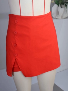 Detail view of red high-waist skort featuring side button decor and a small side slit