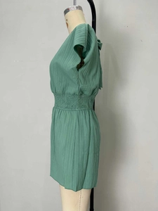 Detail of mint green pleated jumpsuit showing smocked waist and vertical fabric texture
