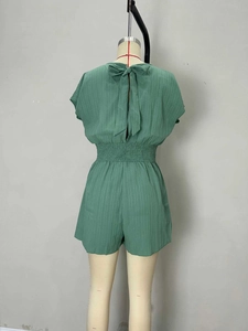 Back view of dark green pleated romper featuring a tie-back bow and elastic waist
