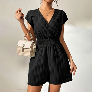 Close-up of black textured v-neck romper with pleated fabric and waist cinching detail