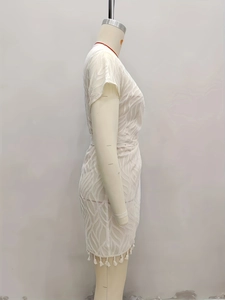 Detail view of white sheer chiffon dress featuring leaf texture and fringe hem