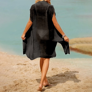 Back view of a long black sheer beach cover-up on a woman walking by the ocean