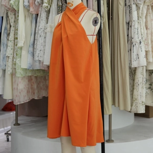 Détail d'une robe trapèze orange à licou pour femme sur un mannequin de couture