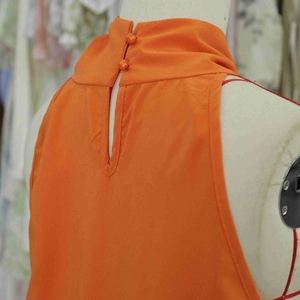 Vue détaillée du dos nu avec découpe goutte d'eau et boutons orange sur la robe d'été