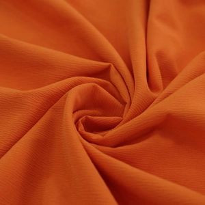 Détail du tissu en mousseline orange vif avec texture plissée fine et drapé doux