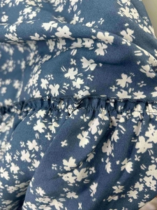 Détail du tissu en mousseline bleu marine avec d'élégants motifs de marguerites blanches