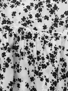Détail macro du tissu floral noir et blanc avec couches plissées et couture d'ourlet délicate