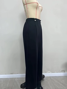Detail of elegant high-waisted wide-leg trousers featuring silver button accents in black