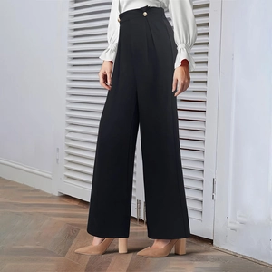 Detail of high waisted black wide leg trousers with decorative metal button for women