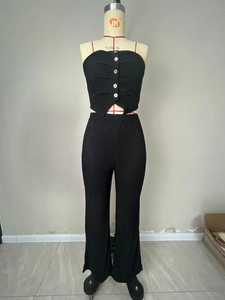 Detail of black pleated fabric top with white contrast buttons and V-cut hemline