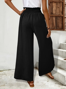 Close-up of black high-waisted wide-leg pants featuring premium pleated texture and elastic waist