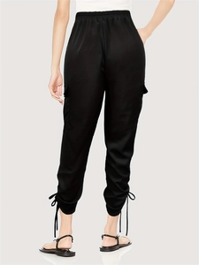 Detail of female black cargo pants showing the elastic waist and silk ankle ribbon tie