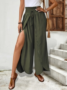 Close-up of high-waisted wide-leg pants in dark green featuring side slits and tie waist