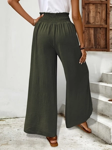 Detail of high waist elastic waistband on olive green wide leg pants with pleated texture