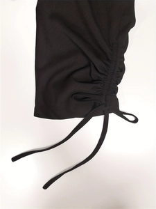 Close-up of side drawstring ruching and hanging ties on black causal trousers
