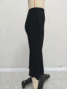 Detail of elegant black pleated knit midi skirt showing high-elasticity fabric texture
