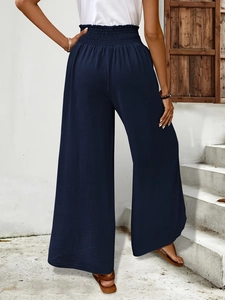 Detailed view of elastic high waist and navy blue textured fabric on wide-leg trousers