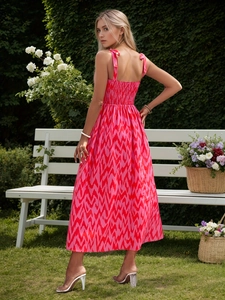 Detail of smocked back and bow tie shoulder straps on a pink floral vacation midi dress