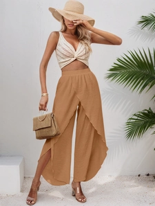 Detail of elegant mustard yellow wide-leg beach trousers with a high-slit wrap design