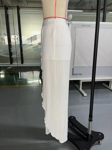 Detail view of white pleated long skirt featuring semi-transparent fabric and side slit