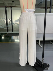 Detail of high waisted white wide leg trousers featuring elegant vertical pleated texture