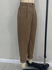 Detail of brown corduroy pants featuring high elastic waist and cuffed hem