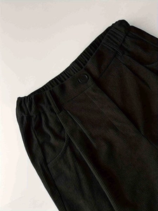 Detail of high waist corduroy pants featuring elastic back and button closure