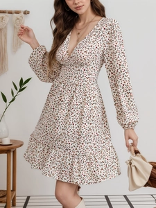 Detalle de vestido floral con cuello en V, cintura elástica y dobladillo de volantes blanco