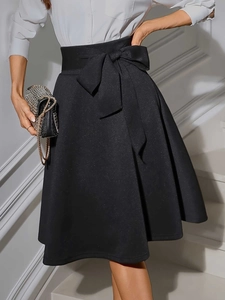 Détail d'une jupe évasée taille haute avec finition métallisée et ceinture à nœud élégante