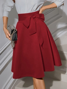 Détail de jupe évasée bordeaux à taille haute avec une ceinture à nœud élégante