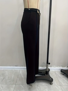 Detailed side view of high-waisted black trousers with metal chain belt accessory