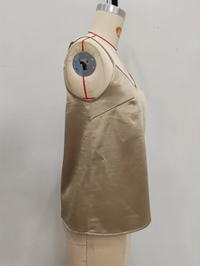 Detailansicht eines champagnerfarbenen Satin-Tops mit dünnen Trägern und feinen Nähten