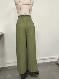 Detail of high waist smocked elastic waistband on grass green wide leg pleated trousers
