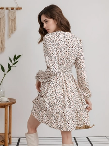 Detalle de vestido floral con cuello en V, manga larga y volantes en la cintura ajustada