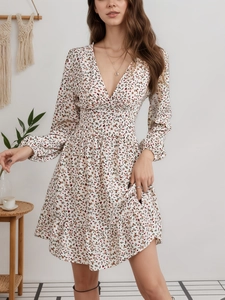 Detalle del mini vestido floral con cuello en V, manga larga y cintura ajustada en beige
