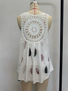 Detail of bohemian white sleeveless top showing intricate lace hollow out back and feather print