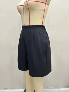 Detailed view of high-waisted shorts featuring front pleats and an elastic back waistband