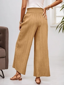 Detail of high waisted wide leg trousers with vertical pleated texture and elastic waistband