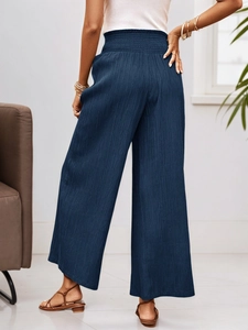 Detail view of high waisted navy blue wide leg trousers with elastic pleated waistband
