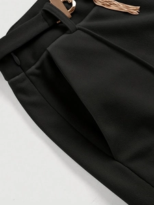High-waisted black straight trousers featuring a gold heart buckle and tassel detail