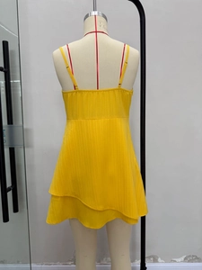 Detail of yellow beach dress showing thin straps and layered hem on a mannequin