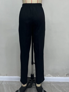 Detail view of the elastic high waist and pocket stitching on black dress pants for women