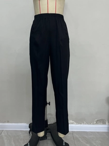 Detailed view of high waist black trousers with elastic waistband and decorative buttons